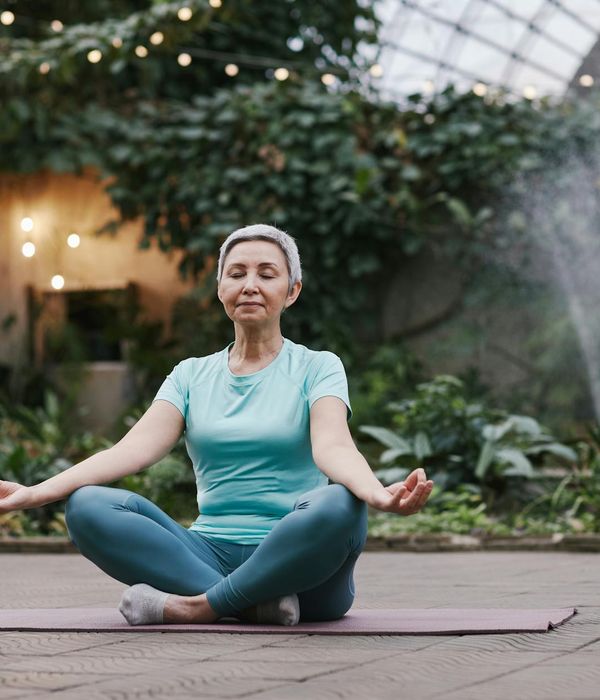 Woman meditating in a serene outdoor setting, glowing with peace.